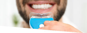 dentist applies teeth whitening kit to patient